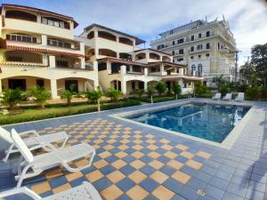 a swimming pool with two chairs and a building at Palm Beach Resort in Boca Chica