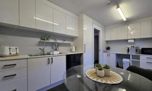 a kitchen with a glass table and white cabinets at Chandelle Park Farm Stay in Exeter