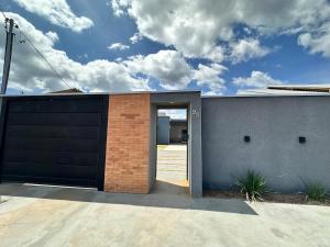 a house with a garage door and a brick wall at Casa 2min do Centro & Piscina in Bonito