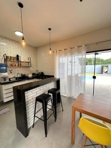 a kitchen with a table and some chairs and a counter at Casa 2min do Centro & Piscina in Bonito