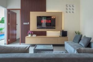 a living room with a couch and a tv at Villa Chandra Lovina in Lovina