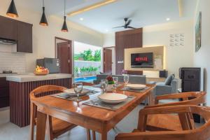 a kitchen and living room with a wooden table and chairs at Villa Chandra Lovina in Lovina