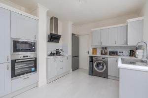a kitchen with white cabinets and a washer and dryer at Modern 2-Bed Sleeps 5 Free Parking and Wifi near Stansted and London in Bishops Stortford +7 photos