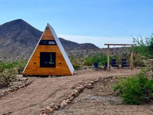 a cabin with a triangular roof on a dirt field at Star Gazer #3 Glamping in Meadview