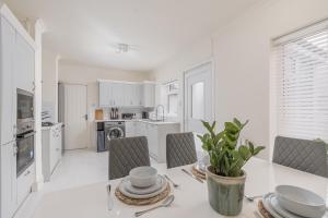 a white kitchen with a table and chairs at Modern 2-Bed Sleeps 5 Free Parking and Wifi near Stansted and London in Bishops Stortford