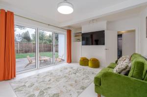 a living room with a green couch and a sliding glass door at Modern 2-Bed Sleeps 5 Free Parking and Wifi near Stansted and London in Bishops Stortford