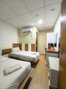 a hotel room with two beds and a desk at Tang Hotel in Alor Setar