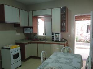 a kitchen with white cabinets and a table and a table and a table at Casa do Descanso in Triunfo