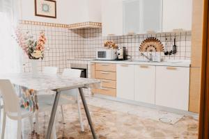a kitchen with white cabinets and a table with chairs at I due ponti in Molfetta