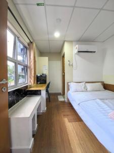 a room with a bed and a desk and a window at Tang Hotel in Alor Setar