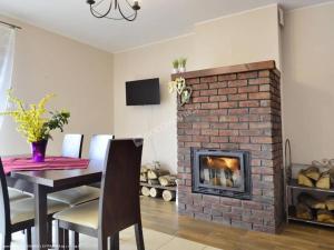 a living room with a brick fireplace and a dining table at Domek Zieleniec I Komfortowy Dom z Sauną dla Dużej Grupy przy Górskich Szlakach in Duszniki Zdrój