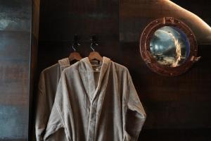 a robe hanging on a rack next to a mirror at Cabin 13 Immersive Suite with Balneotherapy in Boulogne-sur-Mer