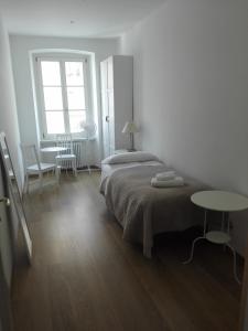 a white bedroom with a bed and a table at Palazzo Brigido Apartment in Trieste