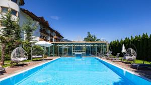 a large swimming pool with chairs and a building at Hotel Magdalena im Zillertal - Urlaub mit Hund in Ried im Zillertal