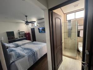 a bedroom with a bed and a bathroom with a shower at Cozy room La Flor in Jacó