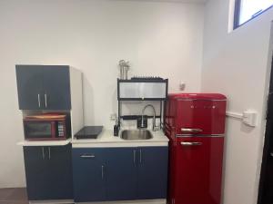 a kitchen with a red refrigerator and a sink at Cozy room La Flor in Jacó
