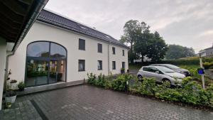 ein weißes Haus mit einem daneben geparkten Auto in der Unterkunft Haus Chresten in Büllingen + 29 Fotos