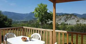a table and chairs on a deck with a view of mountains at ZEcamping 4 étoiles animaux acceptés animations piscine chauffée in Rosans
