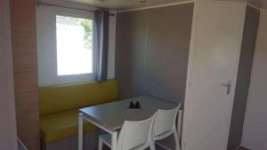 a small dining room with a table and two white chairs at ZEcamping 4 étoiles animaux acceptés animations piscine chauffée in Rosans