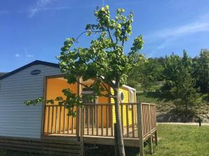 a tiny house with a porch and a tree at ZEcamping 4 étoiles animaux acceptés animations piscine chauffée in Rosans