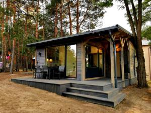a small cabin with a porch and a table and chairs at Domki Bliżej Gwiazd in Krasnobród