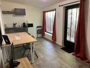 a room with a table and a kitchen with red curtains at T2 Côté Jardin in Eysines