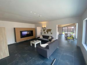 a living room with a couch and a tv at Spacious house specially for workers and expats in Maldegem