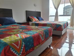 1 dormitorio con 2 camas y mantas de colores. en Hospedaje Familiar Rigimark, en Tacna