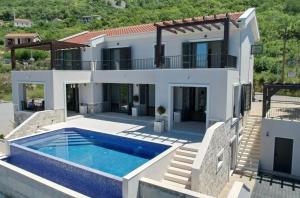 a villa with a swimming pool in front of a house at Villa Miramare in Blizikuće