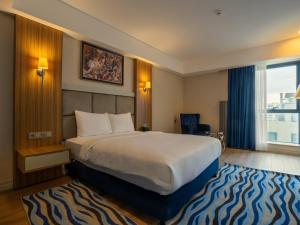 a hotel room with a large bed and a window at Elite World Comfy Diyarbakır in Diyarbakır