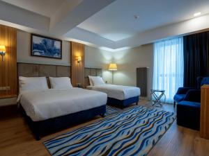 a hotel room with two beds and a blue couch at Elite World Comfy Diyarbakır in Diyarbakır +11 photos