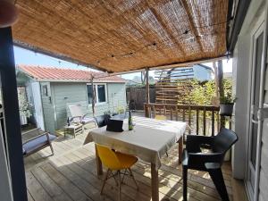 a patio with a table and chairs on a deck at Maison 47m2 climatisé, piscine,linge fourni in Gujan-Mestras