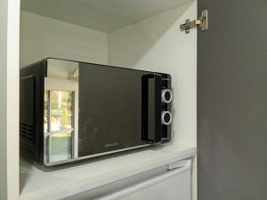 a microwave sitting on top of a shelf at EVASION LOUE #5 x2 people "La POTERIE" in Lods