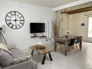a living room with a table and a clock on the wall at Gite du Trefoux logement le Villainois in Villaines-la-Gonais