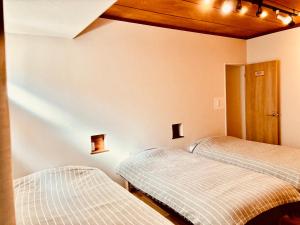 two beds in a room with lights on the wall at 波止場の海まで徒歩30秒の貸切宿 "ギョグンミニ" "Gyogun Mini" in Ainan