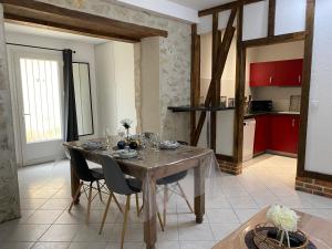 a dining room with a table and chairs and a kitchen at Gite du Trefoux logement le Villainois in Villaines-la-Gonais