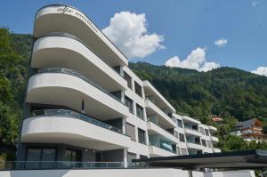 a large white building with mountains in the background at Sun Terrace Apartment 04 I Gerlitzen-Ossiachersee I Alpe Maritima in Annenheim