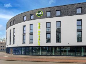 a large white building with a yellow sign on it at B&B Hotel Krefeld-City in Krefeld