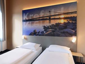 two beds in a room with a painting on the wall at B&B Hotel Krefeld-City in Krefeld