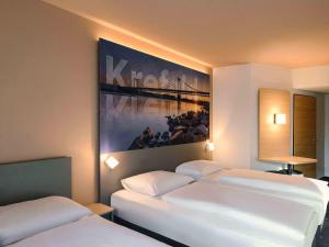 two beds in a room with a painting on the wall at B&B Hotel Krefeld-City in Krefeld +21 photos