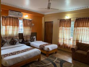 a bedroom with two beds and a couch and windows at Hotel The Mint Garden in Pokhara +31 photos