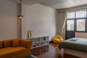 a bedroom with a bed and a couch and a window at Arunne in Bangkok Yai