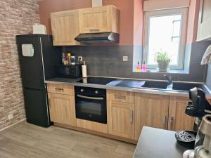 a kitchen with wooden cabinets and a black refrigerator at Mer Méditerranée et Béziers à 10min Parking gratuit in Sauvian