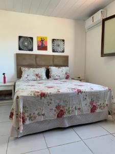 a bedroom with a large bed with a floral bedspread at casa aconchegante proximo a praia in Maceió