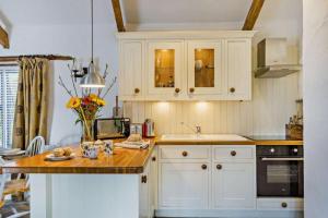 a kitchen with white cabinets and a wooden counter top at Cobble Cottage in Cardinham +7 photos