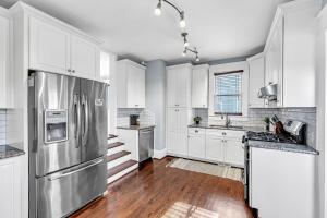 a kitchen with white cabinets and a stainless steel refrigerator at Historic Home with King Bed in High Point