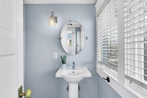 a white bathroom with a sink and a mirror at Historic Home with King Bed in High Point +14 photos