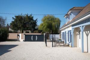 a building with a gate and a table in a driveway at La maison bleue in Lusigny-sur-Barse