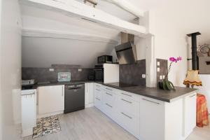 a kitchen with white cabinets and black appliances at La maison bleue in Lusigny-sur-Barse +12 photos