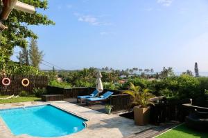 a swimming pool in a yard with a chair and a patio at Planet Scuba Bed and Breakfast in Ponta do Ouro